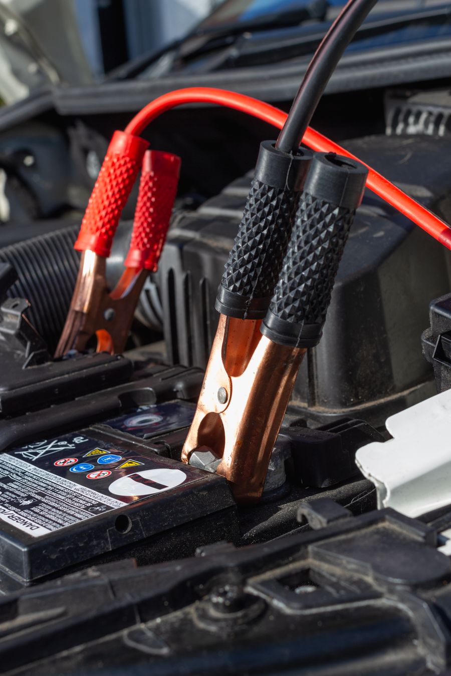 Jumper cable clamps attached to a vehicle battery