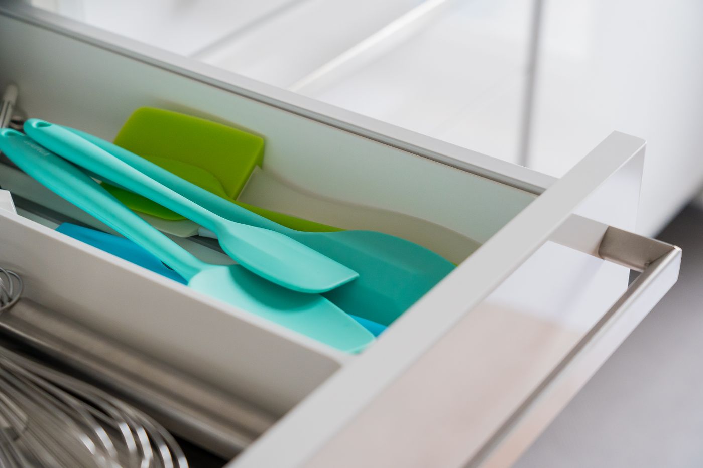 Silicone kitchen spatulas and a whisk in an organized drawer