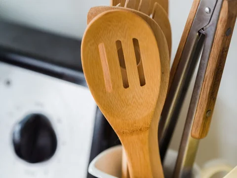 Wooden and metal kitchen utensils in a white container