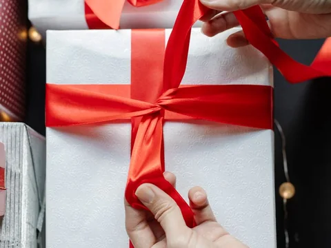 Tying a red ribbon around a white gift box
