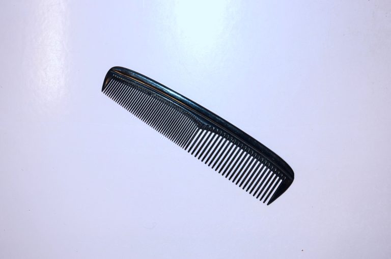 A black hair comb against a pale background