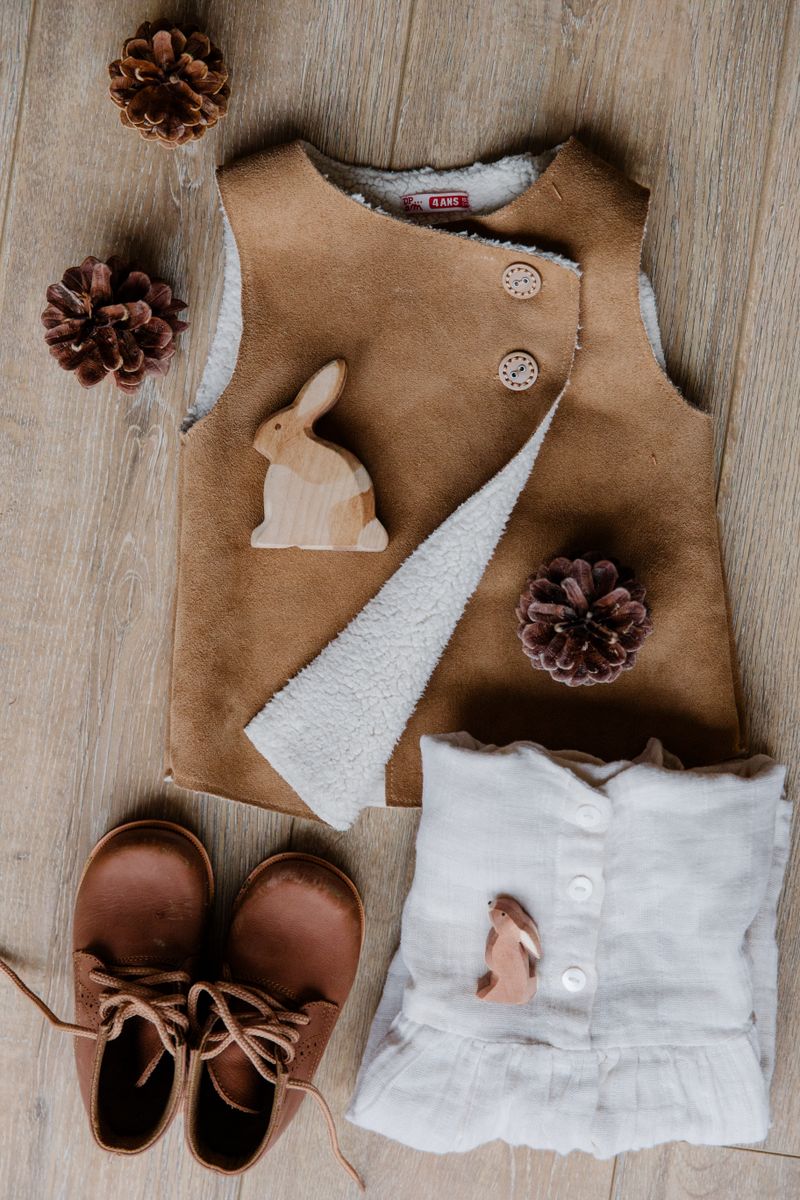 Baby clothes and shoes arranged on a wooden surface