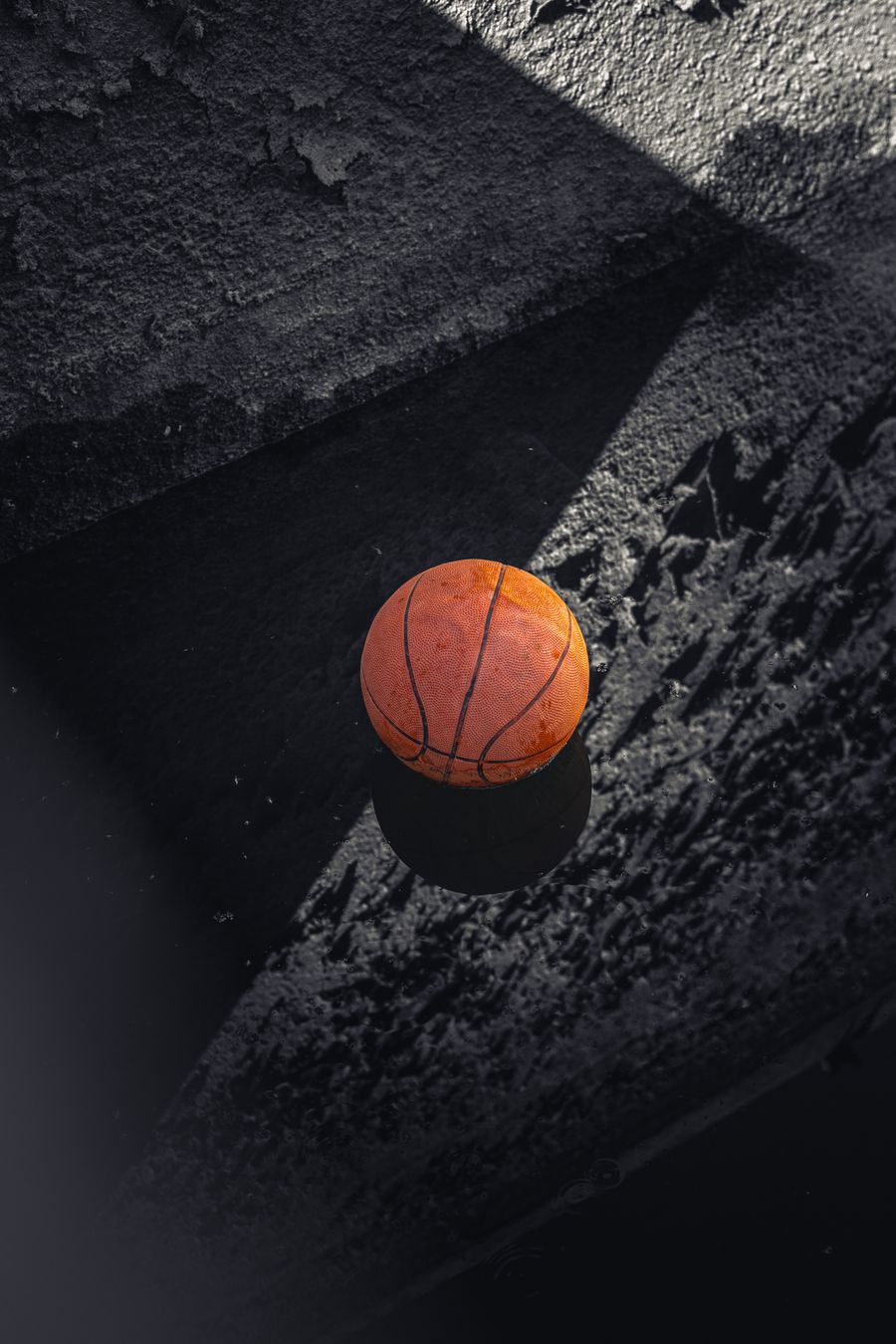 Orange basketball resting on a dark outdoor court