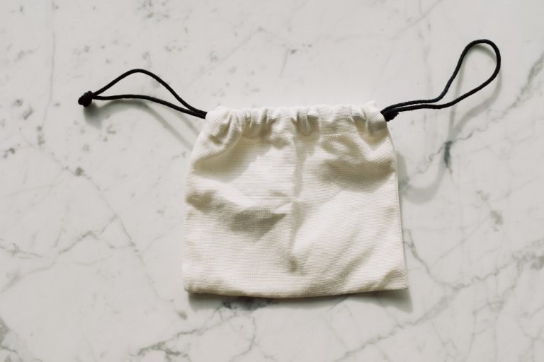 A plain cotton drawstring pouch on a light surface