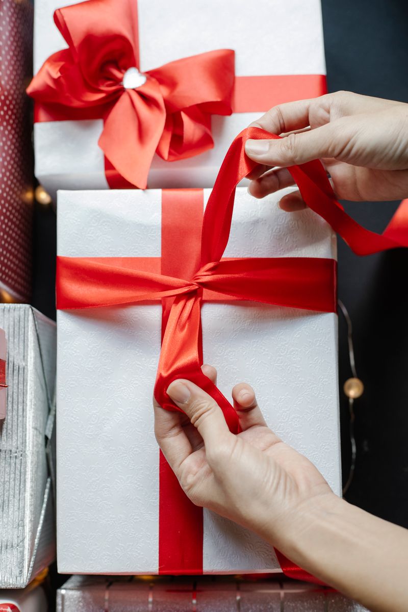 Tying a red ribbon around a white gift box
