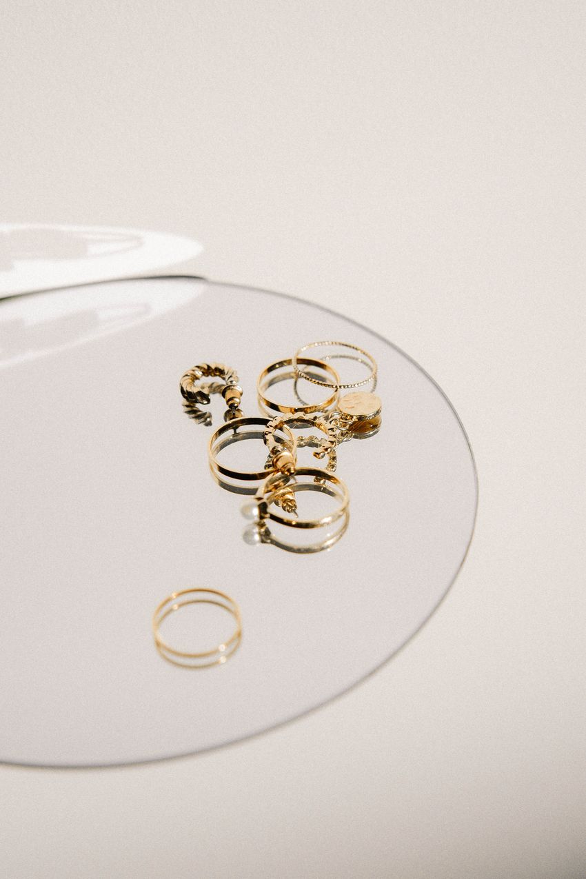 Gold-colored fashion rings arranged on glass