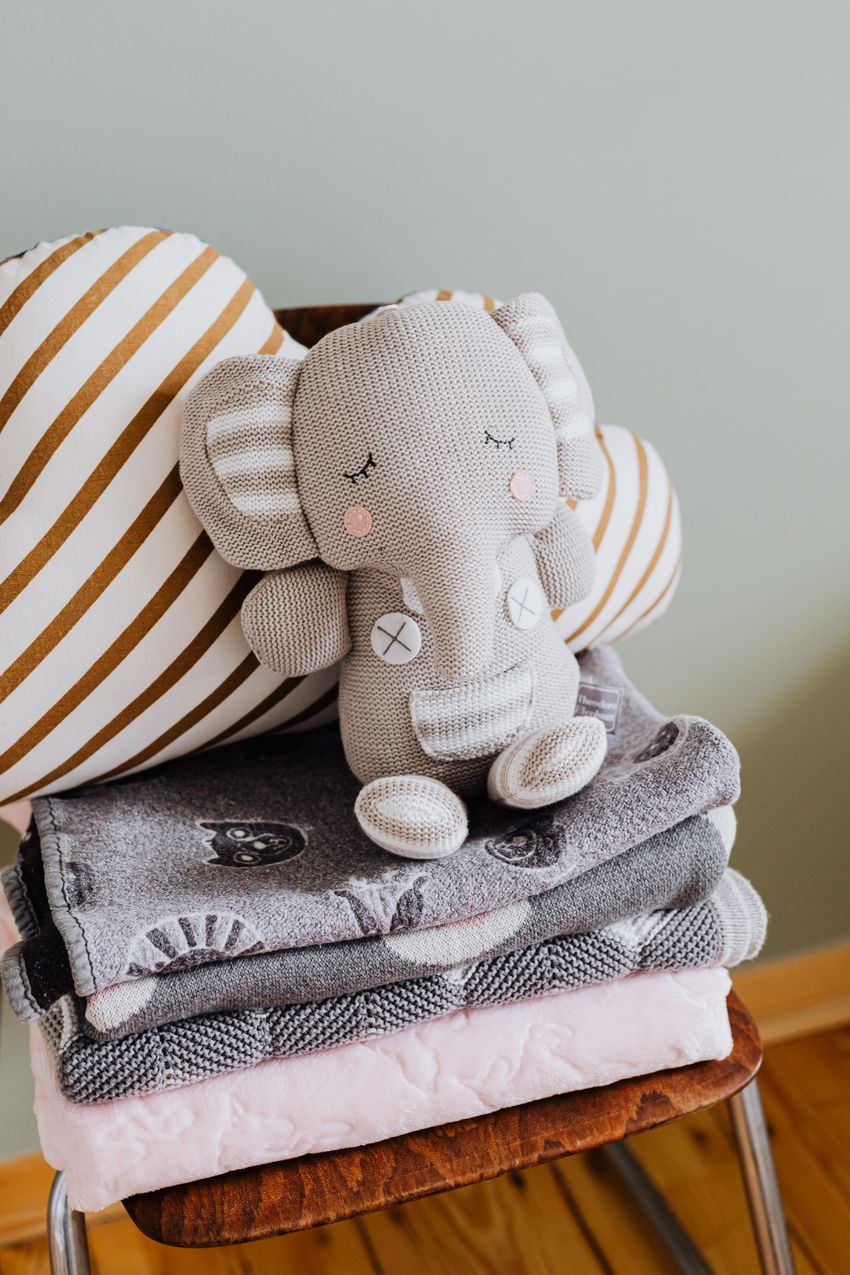 Folded nursery textiles with a knitted elephant display prop